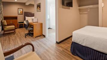 Una habitación de hotel con cama, escritorio, silla y televisor.