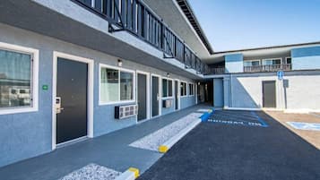 A building with a series of doors and windows, a parking area with handicapped parking spaces, and a clear sky.