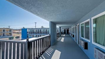 A corridor with a balcony on one side, featuring a metal railing and a blue exterior.
