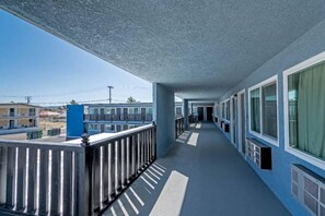 A corridor with a balcony on one side, featuring a metal railing and a blue exterior. - 2 Queen Beds | Non-Smoking, Micfridge (Ridgecrest CA)
