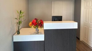 En receptionsdisk med en vas med blommor och en svart stol.