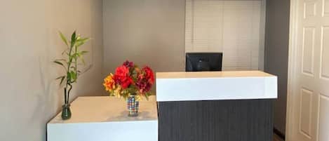 A reception desk with a vase of flowers and a black chair.