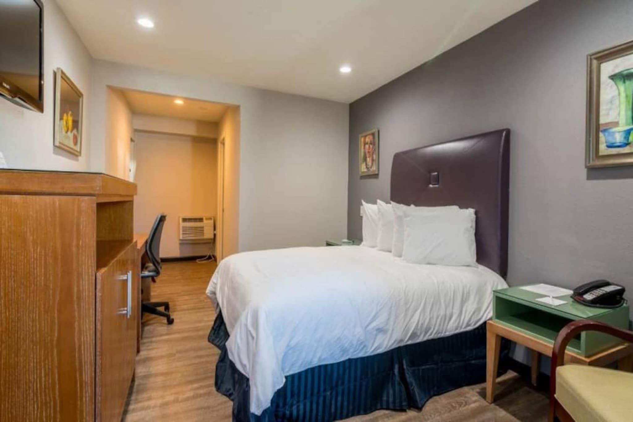Habitació d'hotel amb un llit, escriptori, cadira i telèfon.