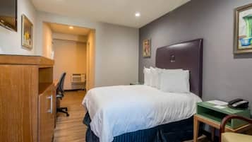 Una habitación de hotel con cama, escritorio, silla y teléfono.