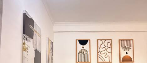 A living room with a brown sofa, a wooden coffee table, and three wall-mounted abstract art pieces.