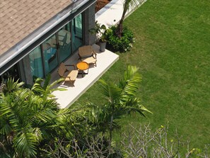 A modern house with a patio area featuring outdoor furniture and a glass enclosure. - Art-filled 6-bedroom villa, 12 m pool & walled garden – Layan, near Bang Tao (Tambon Choeng Thale)
