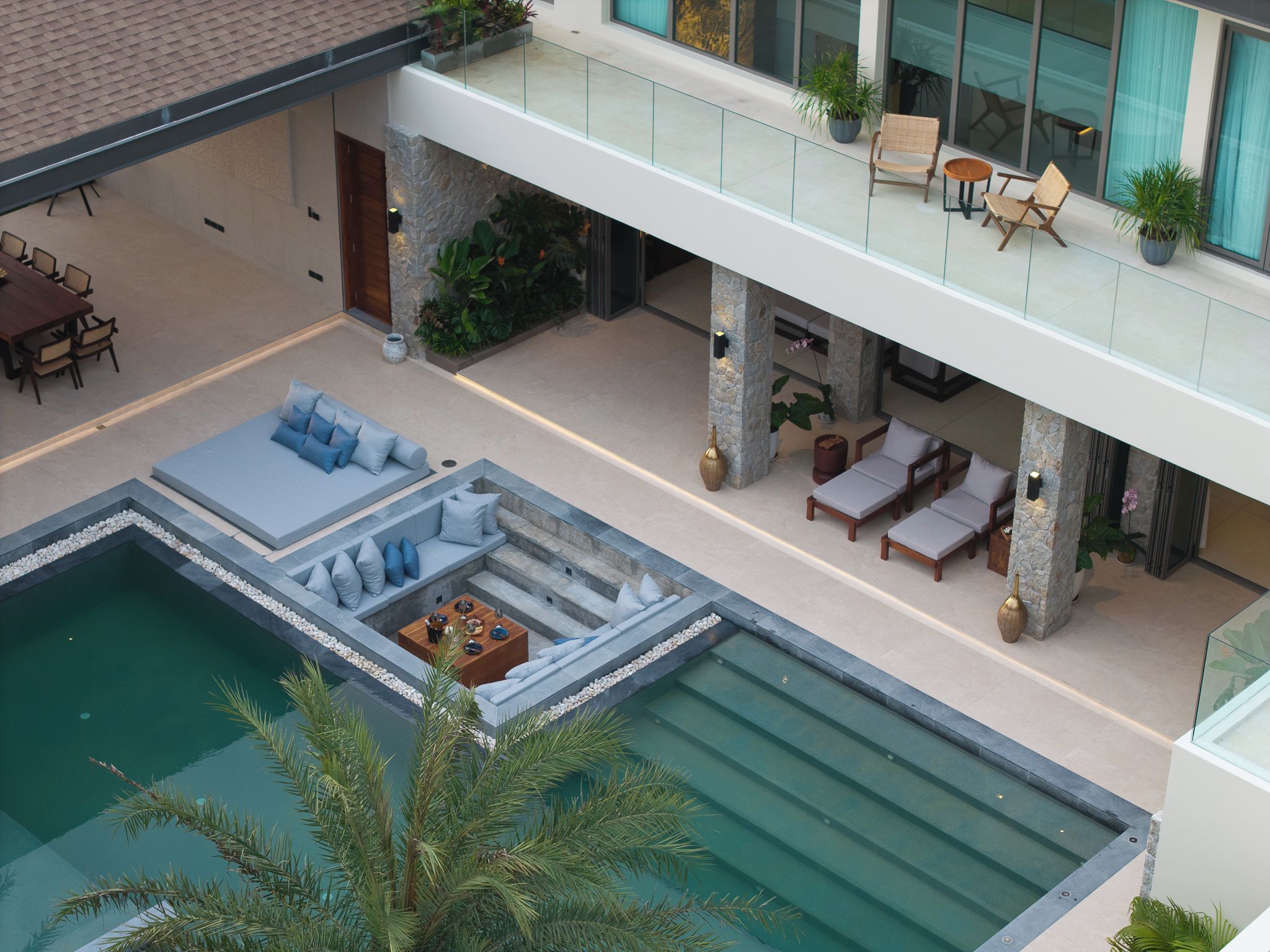 A modern outdoor pool area with lounge seating and a dining setup.