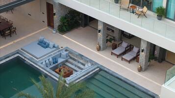 A modern outdoor pool area with lounge seating and a dining setup.