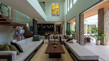 A spacious living area with a central coffee table, sofas, and a staircase leading to an upper level.