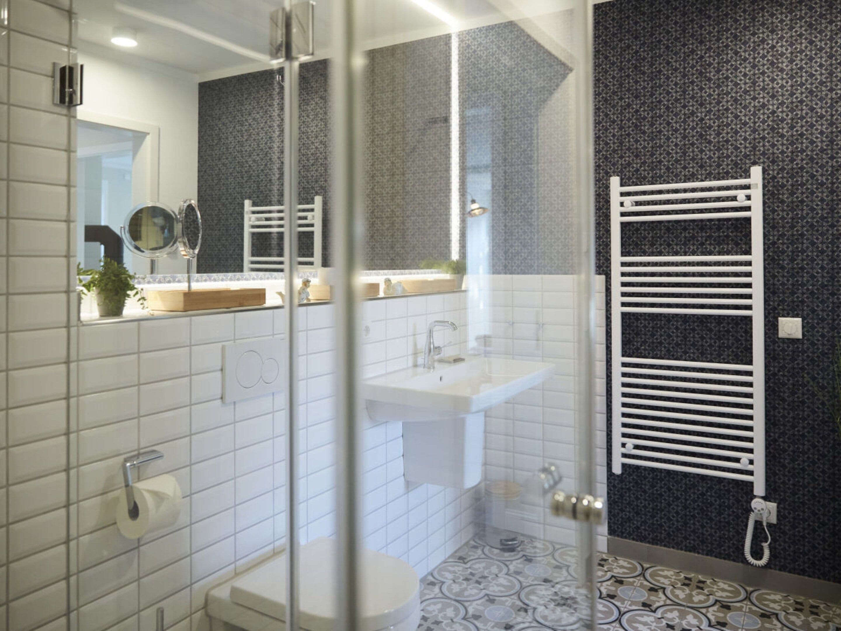 Un baño moderno con cabina de ducha de vidrio, un lavabo blanco y un perchero para toallas.