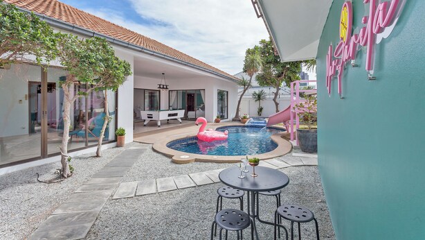 A pool area with a pink flamingo float, a billiards table, and a seating area with a table and chairs. - 3-bedroom house in awesome Pattaya City with AC comfort (Pattaya City)