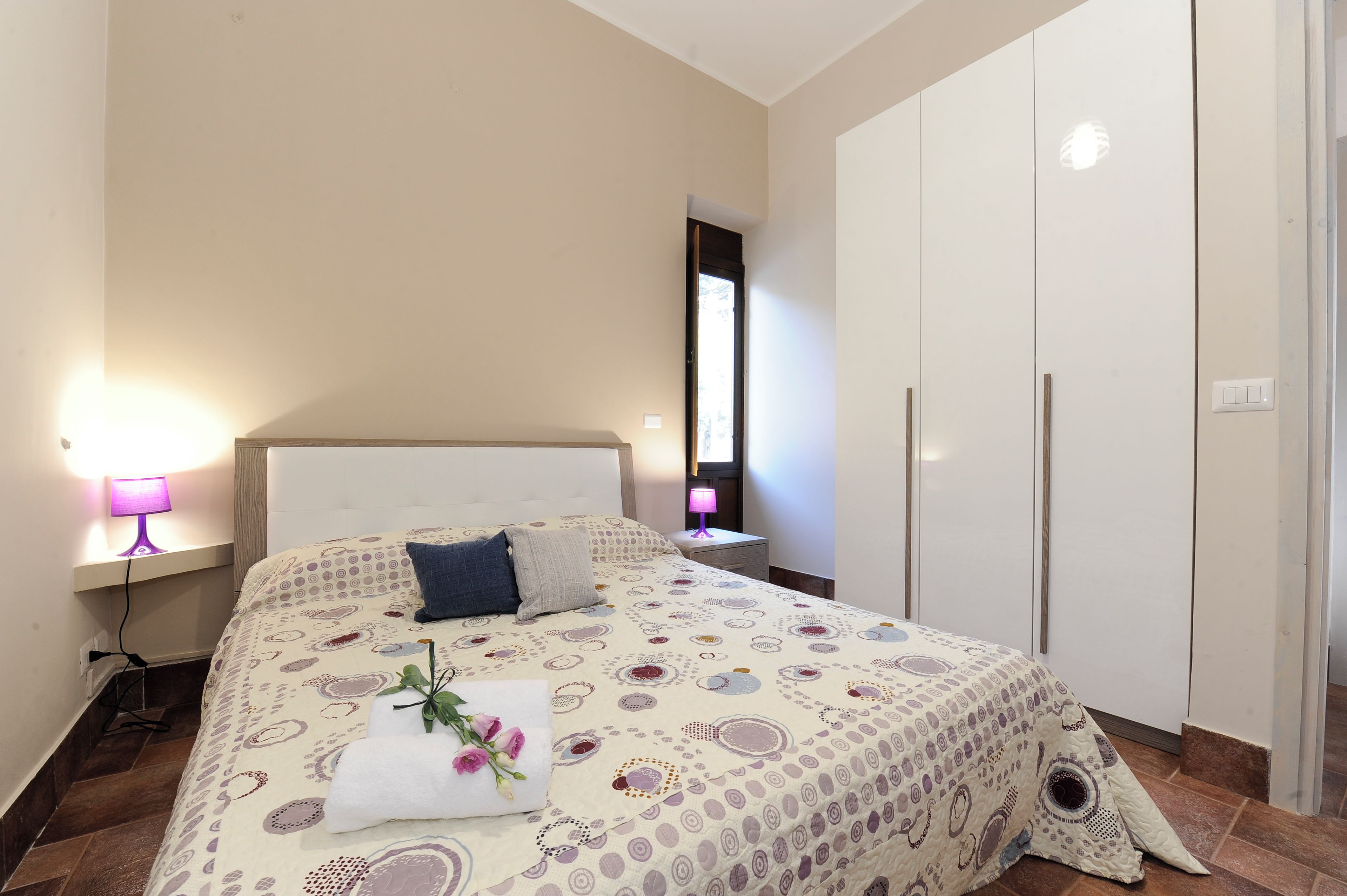 Une chambre à coucher avec un lit, des lampes de chevet, une table de chevet, une armoire et un miroir.