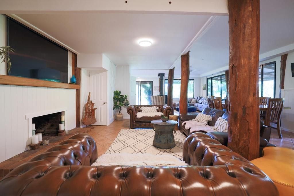 A spacious living room with leather sofas, a fireplace, and large windows.