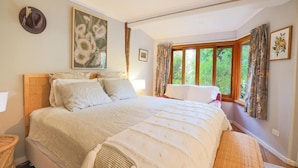 Un dormitorio con una cama grande, una ventana con cortinas y un cuadro en la pared.