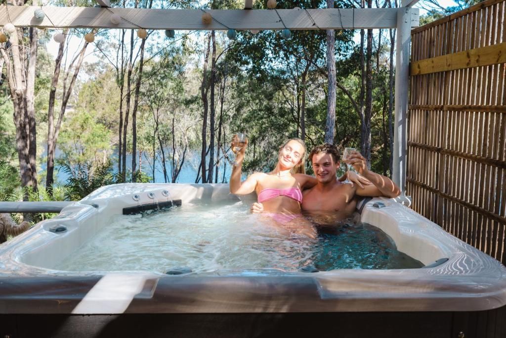 Un jacuzzi con una pérgola de madera encima, rodeado de árboles.