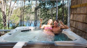 Un jacuzzi con una pérgola de madera encima, rodeado de árboles.