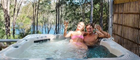A hot tub with a wooden pergola overhead, surrounded by trees.