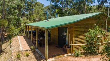 A wooden cabin with a green roof, surrounded by trees.