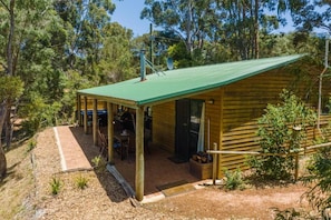 A wooden cabin with a green roof, surrounded by trees.