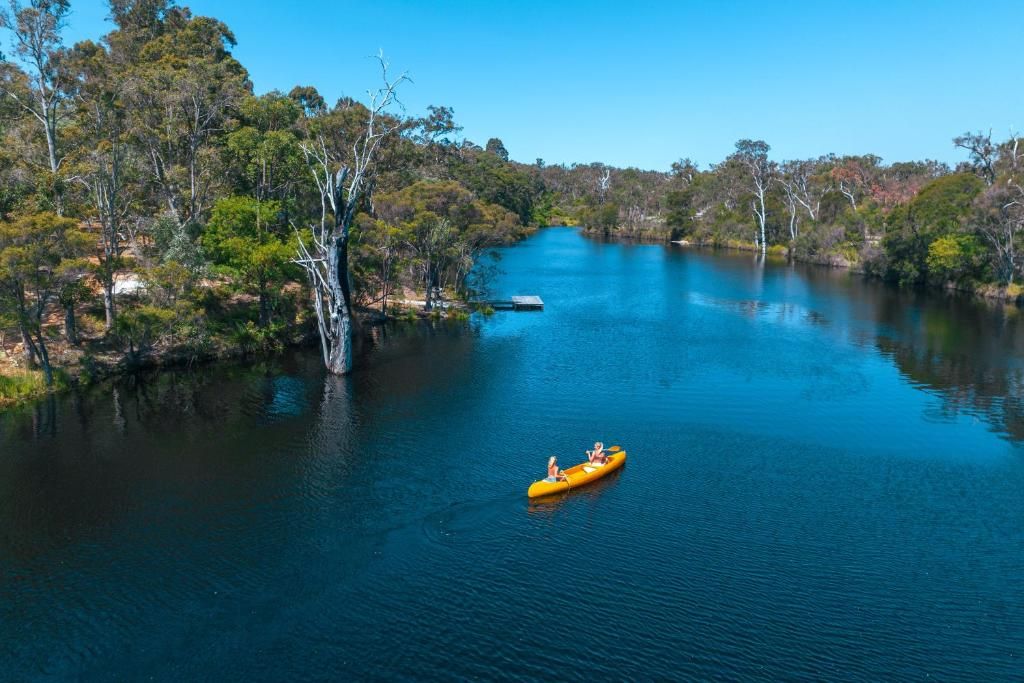 Un río tranquilo con una balsa amarilla, rodeado de árboles frondosos y cielos despejados.