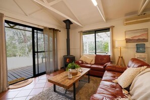 Uma sala de estar acolhedora com lareira, sofá de couro e mesa de centro de madeira.