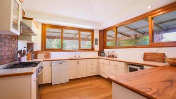 A modern kitchen with wooden cabinets, a dishwasher, and a large window providing natural light.
