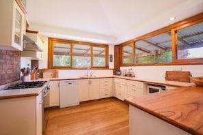 A modern kitchen with wooden cabinets, a dishwasher, and a large window providing natural light.