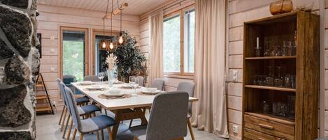 Ein Essbereich mit einem langen Tisch, gedeckt für sechs Personen, umgeben von Stühlen, mit einem Holzkasten zur Rechten.