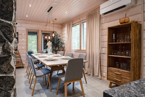 En matplats med ett långt bord som är dukat för sex personer, omgivet av stolar, och ett träskåp till höger.