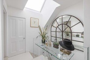 A modern interior with a glass display case, a door, a framed artwork, and a skylight. - The Harley Street Penthouse, by Veeve (London)