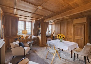Ein Zimmer mit Holzboden, einem Esstisch mit weißem Tischläufer und einer Couch.
