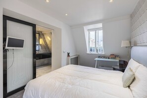 Ein modernes Schlafzimmer mit Bett, Schreibtisch und Fernseher.