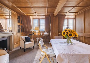Ein Zimmer mit Kamin, einem Esstisch mit Sonnenblumen und einer Couch.