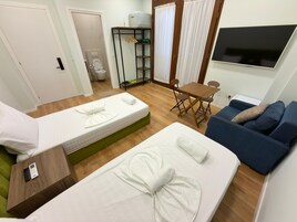 A hotel room with two beds, a sofa, a TV, and a small table.