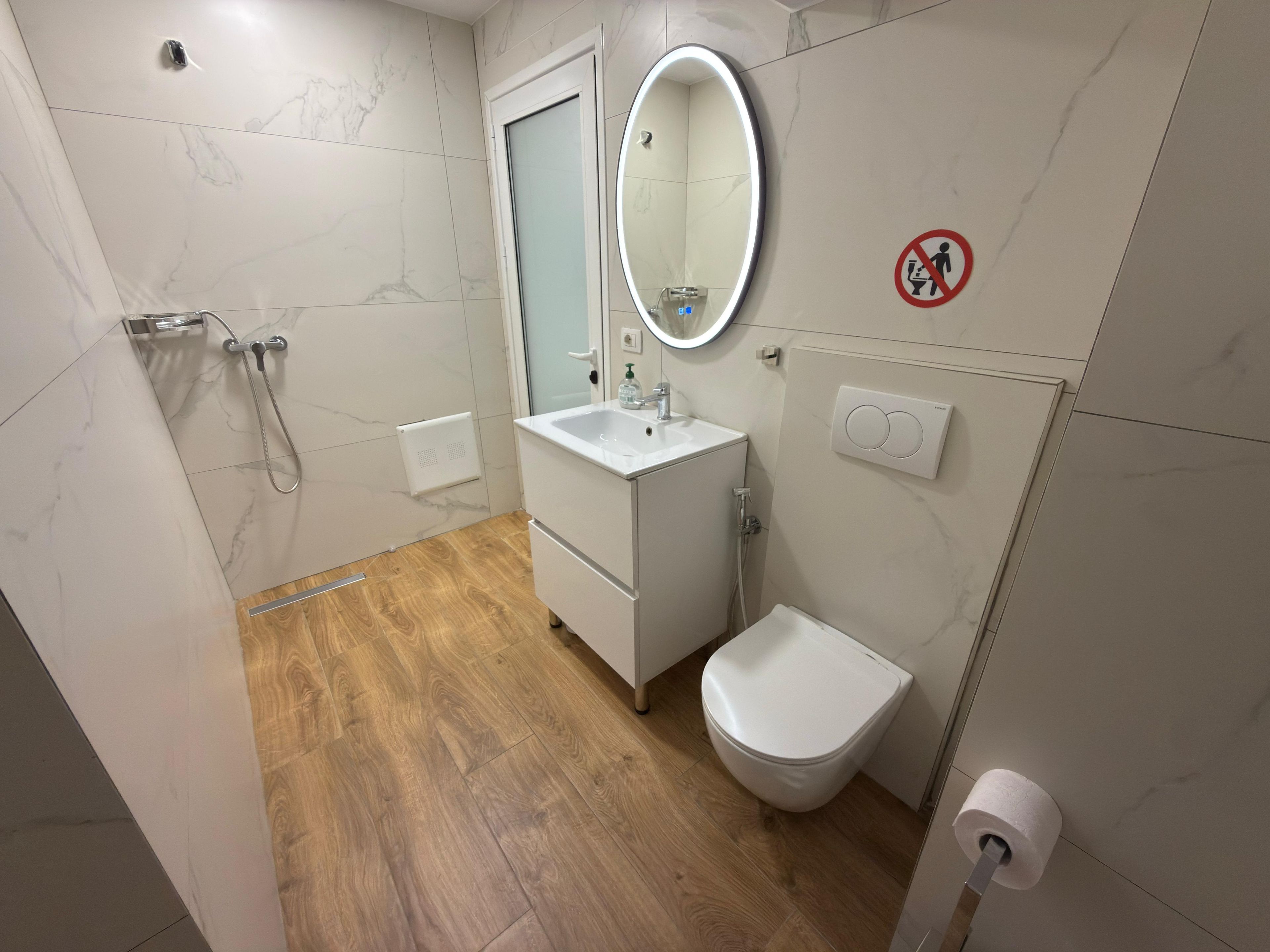 A bathroom with a shower, sink, toilet, and a mirror.