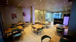 A dining area with wooden tables and chairs, a piano, and artwork on the walls. - Rali Hotel & Restaurant (Tirana)