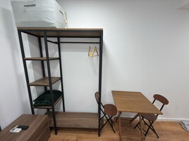 A compact room with a bunk bed, a small table, two chairs, and a wooden floor.