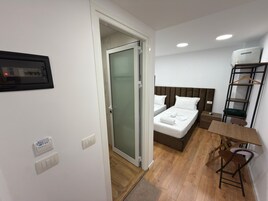Una habitación de hotel con una cama, mesita de noche y una silla.