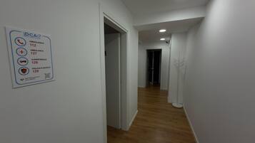 Un corridoio con un cartello che elenca i numeri di contatto di emergenza per il DCA Group Dental Center Albania.