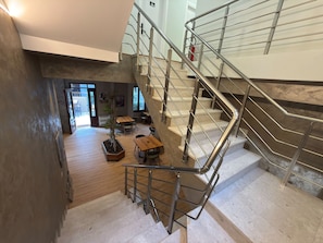 A modern interior with a staircase, a dining area, and a view of the outdoors. - Rali Hotel & Restaurant (Tirana)