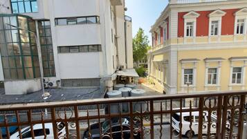 Una vista di strada con edifici, auto parcheggiate e un cancello in metallo.
