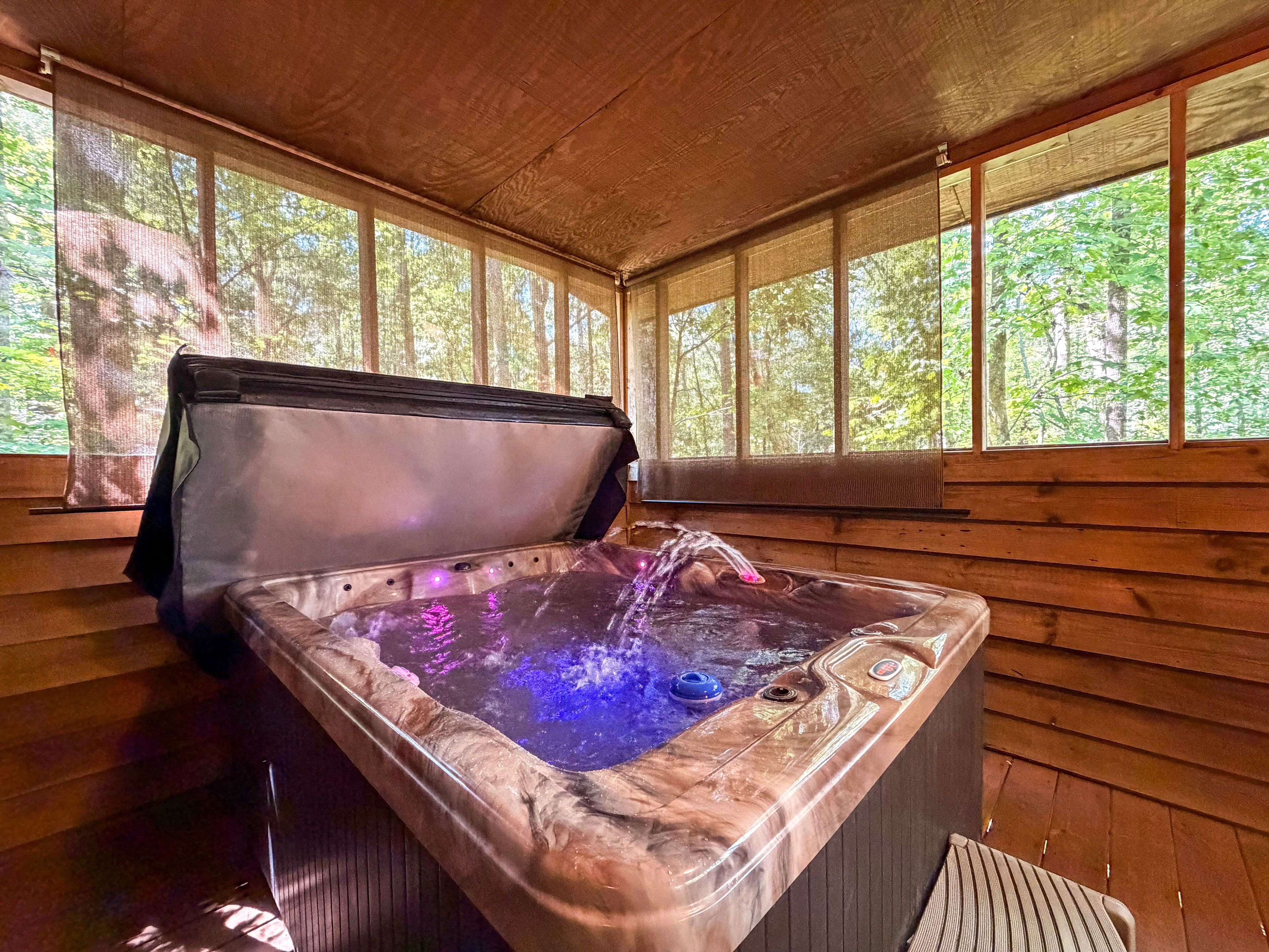A hot tub with a wooden interior and a view of the forest through large windows.