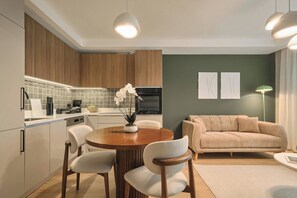 A modern kitchen with wooden cabinets, a dining table with chairs, and a living area with a sofa and a floor lamp. - Karpov, 2br, Peaceful, Welcoming (Istanbul)