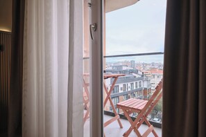 A balcony with a view of a cityscape, a wooden chair, and a window with curtains. - Karpov, 2br, Peaceful, Welcoming (Istanbul)