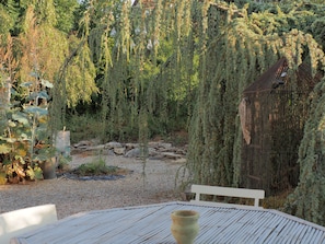 A garden with a wooden bench, a white fence, and a weeping willow tree.