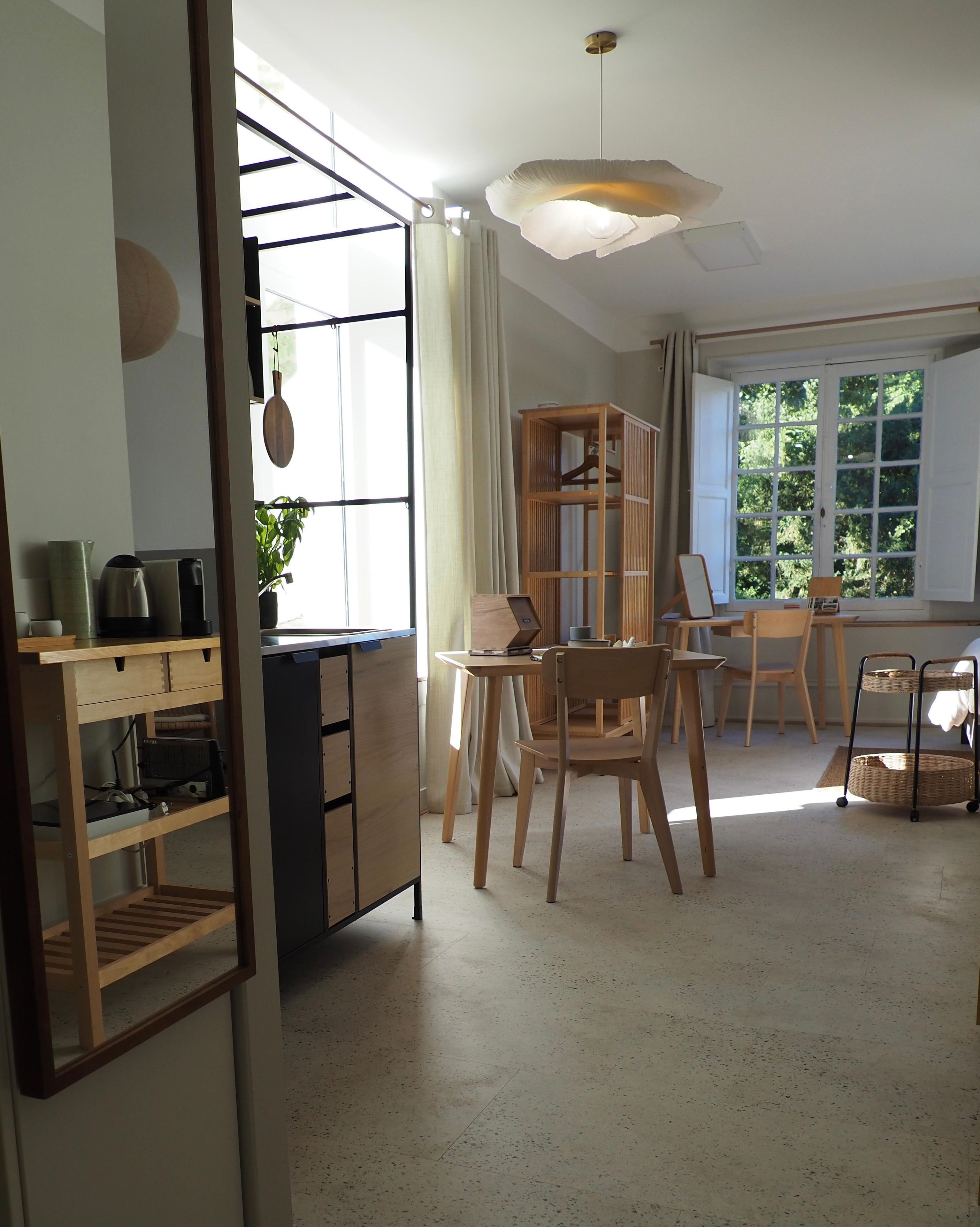 Een goed verlichte kamer met een eethoek, een houten kast en een hanglamp.