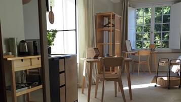 Een goed verlichte kamer met een eethoek, een houten kast en een hanglamp.