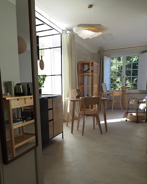 A well-lit room with a dining area, a wooden cabinet, and a hanging light fixture.