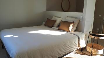 Une chambre à coucher avec un grand lit, une table de chevet, un miroir fixé au mur et un luminaire suspendu.
