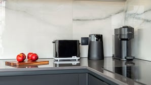 Eine Küche mit modernem Design, inklusive einer Bosch-Kaffeemaschine, einer De'Longhi-Espressomaschine und einem Braun-Toaster.